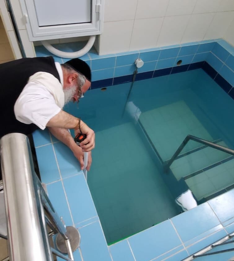 רב כשרות בודק את מפלס המים בבריכת הטבילה